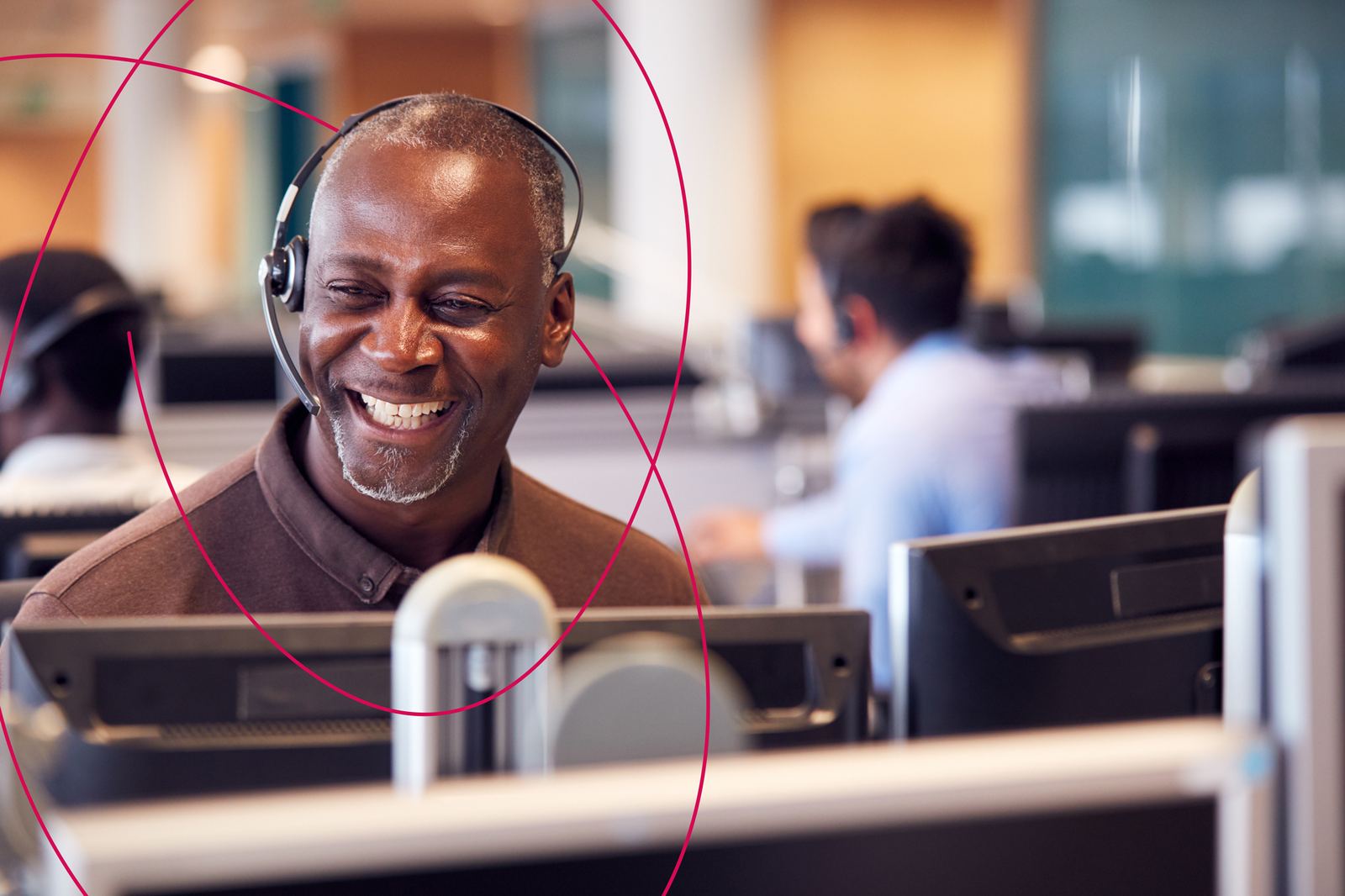 A smiling debt adviser wearing a headset at his desk